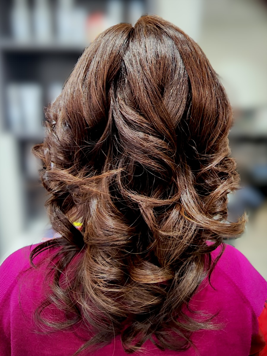 Glossy chocolate-brown hair styled in big, bouncy curls, seen from behind