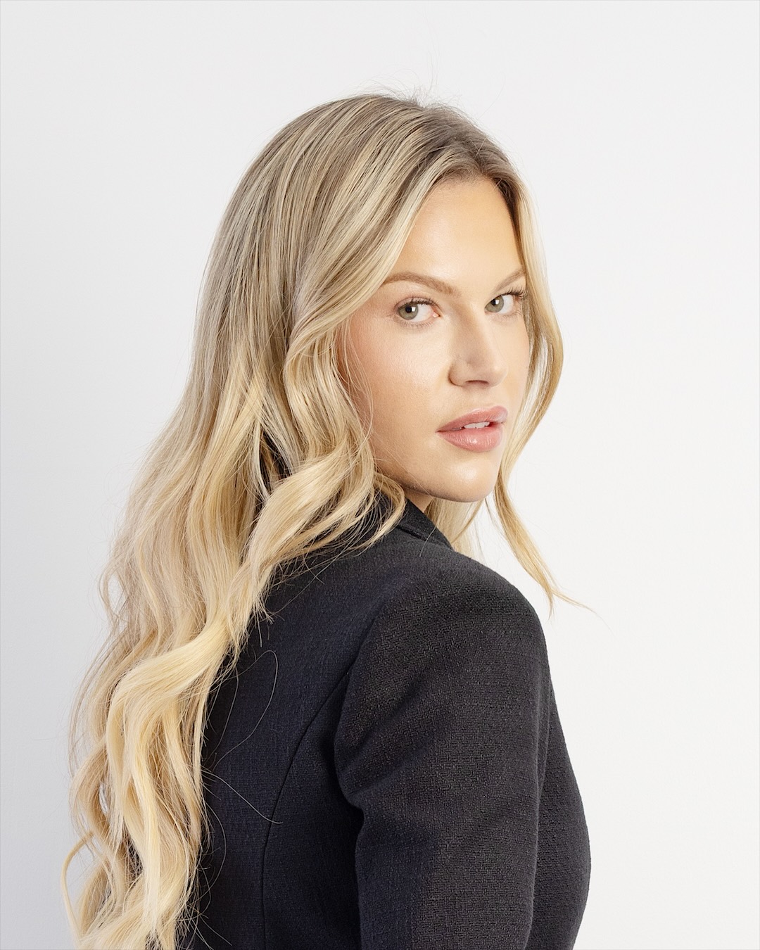 Model with long, warm blonde waves, looking over her shoulder